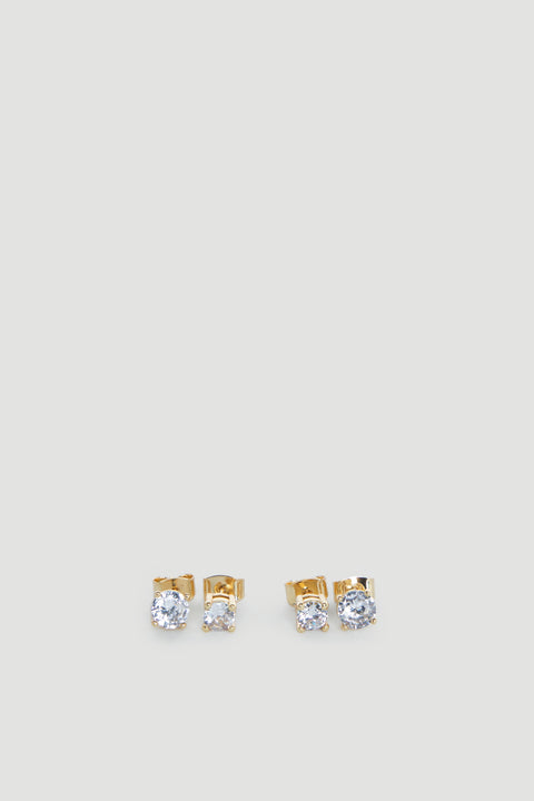 Two pairs of delicate gold stud earrings each featuring sparkling clear stones on a light grey background