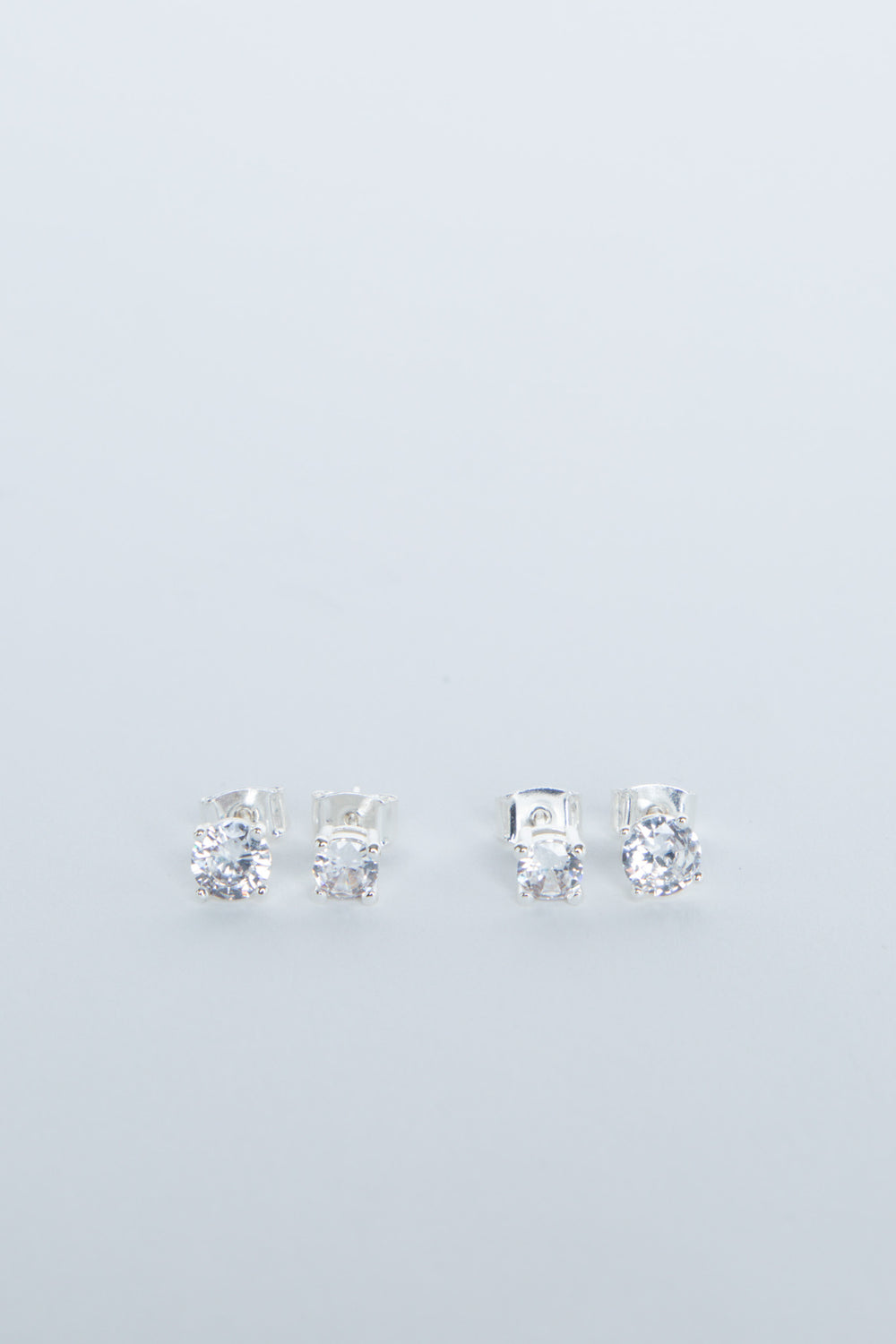 Two pairs of delicate silver stud earrings with sparkling clear stones, minimalist and elegant design for girls.