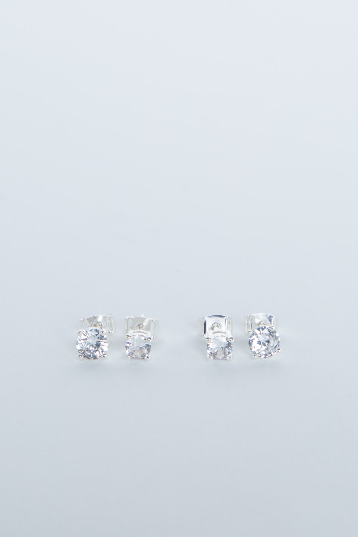 Two pairs of delicate silver stud earrings with sparkling clear stones, minimalist and elegant design for girls.