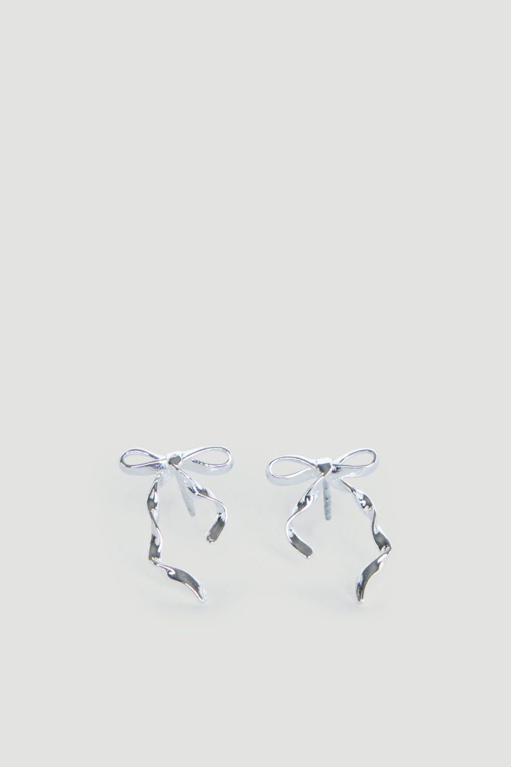 Delicate silver bow-shaped stud earrings with flowing ribbon details, designed for girls with a charming, graceful touch.