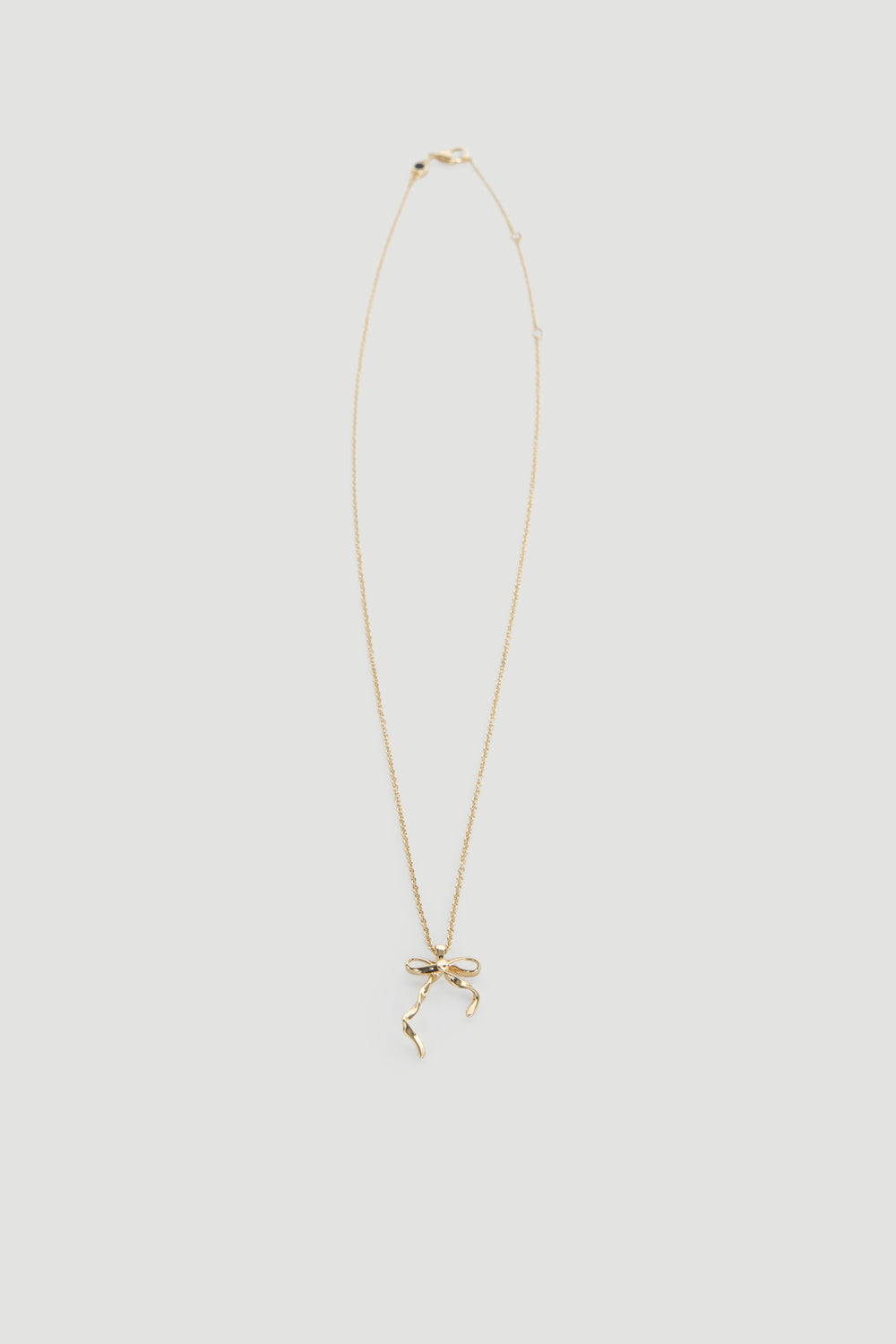 Delicate gold necklace featuring a dainty bow pendant on a fine chain, perfect for everyday wear.