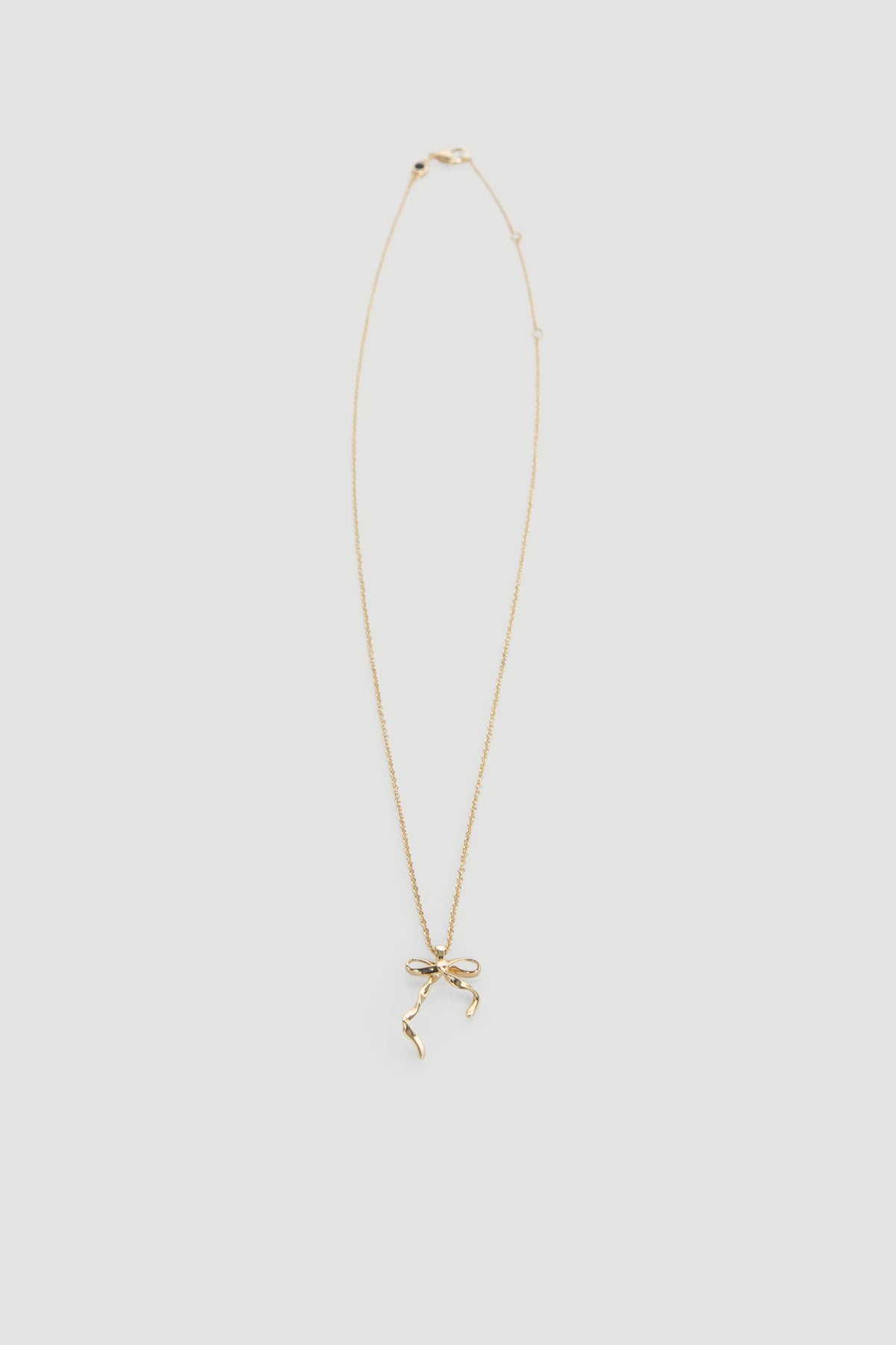 Delicate gold necklace featuring a dainty bow pendant on a fine chain, perfect for everyday wear.