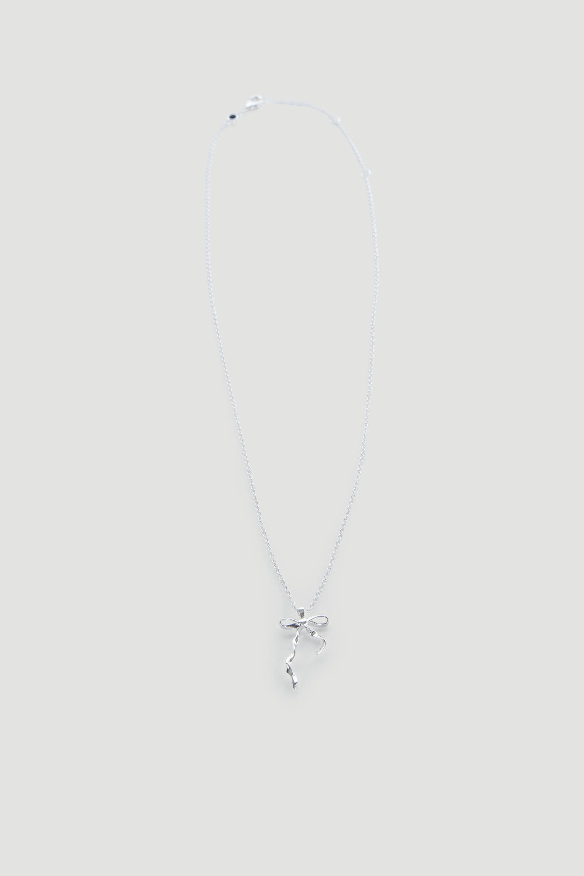 Delicate silver necklace featuring a dainty bow pendant on a fine chain, perfect for everyday wear.