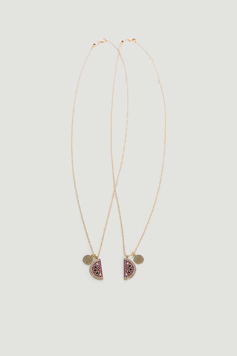 Two delicate gold chains featuring watermelon-inspired pendants with pink and green stones on a neutral background