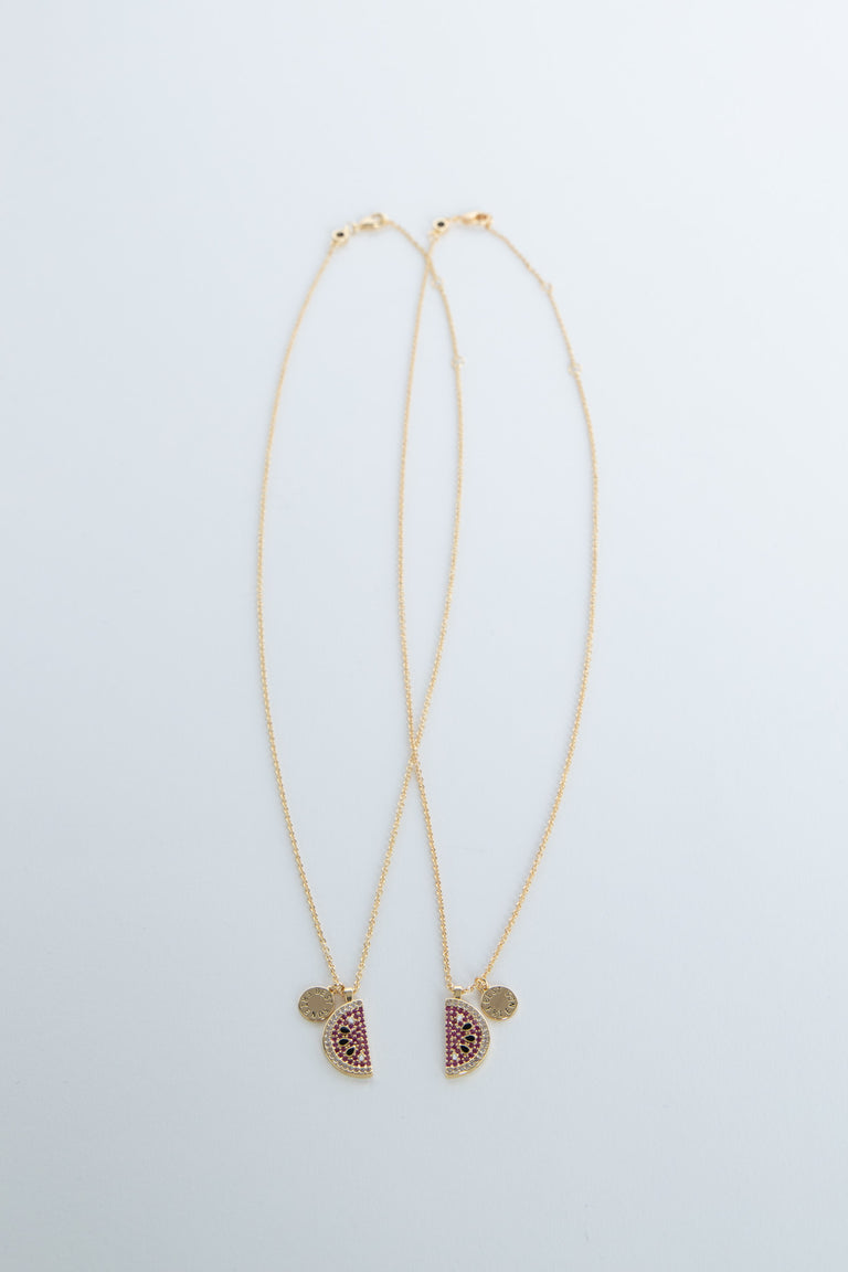 Two delicate 9ct gold necklaces with watermelon-shaped pendants adorned with pink and green stones on thin chains.