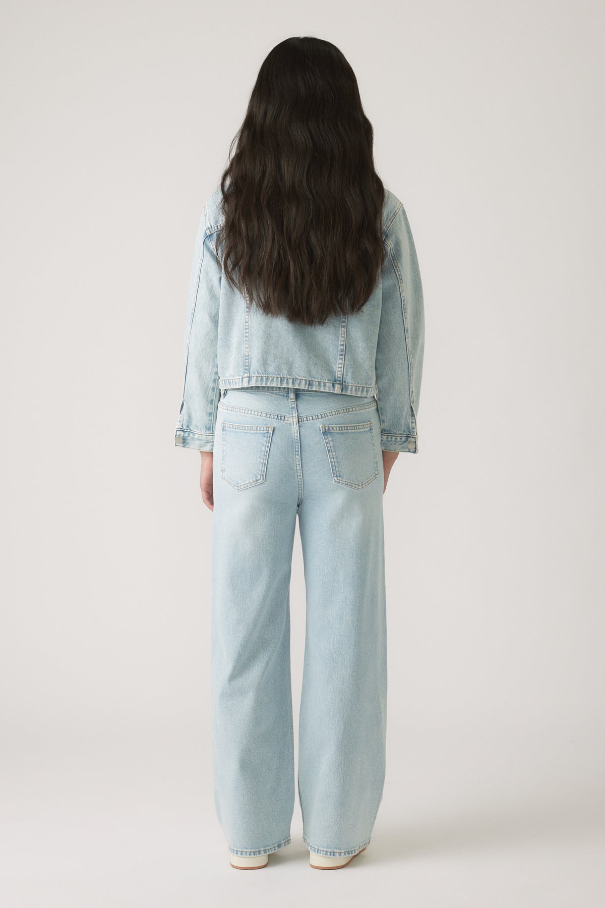 Girl shown from behind wearing a light wash Girls Embellished Denim Jacket with matching wide-leg jeans by DECJUBA.