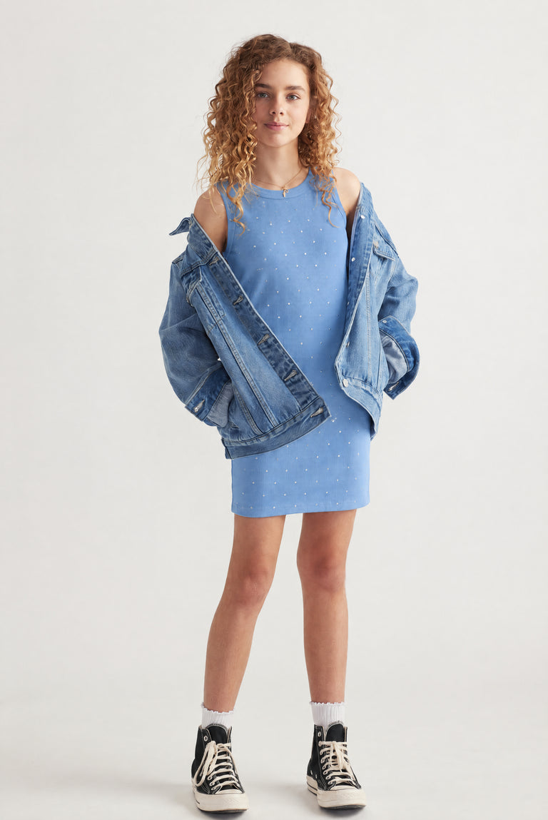 Girl wearing a blue sleeveless crystal dress with an oversized denim jacket and sneakers