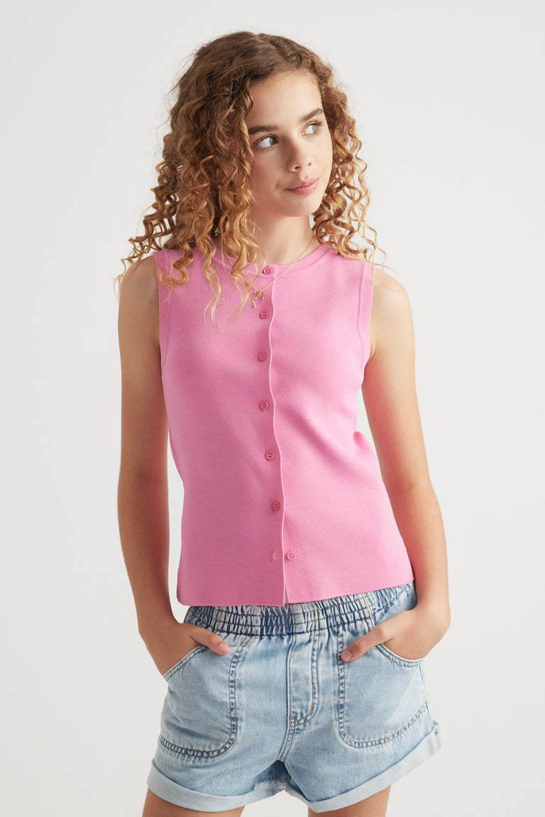 Girl wearing a pink sleeveless button through knit vest with denim shorts
