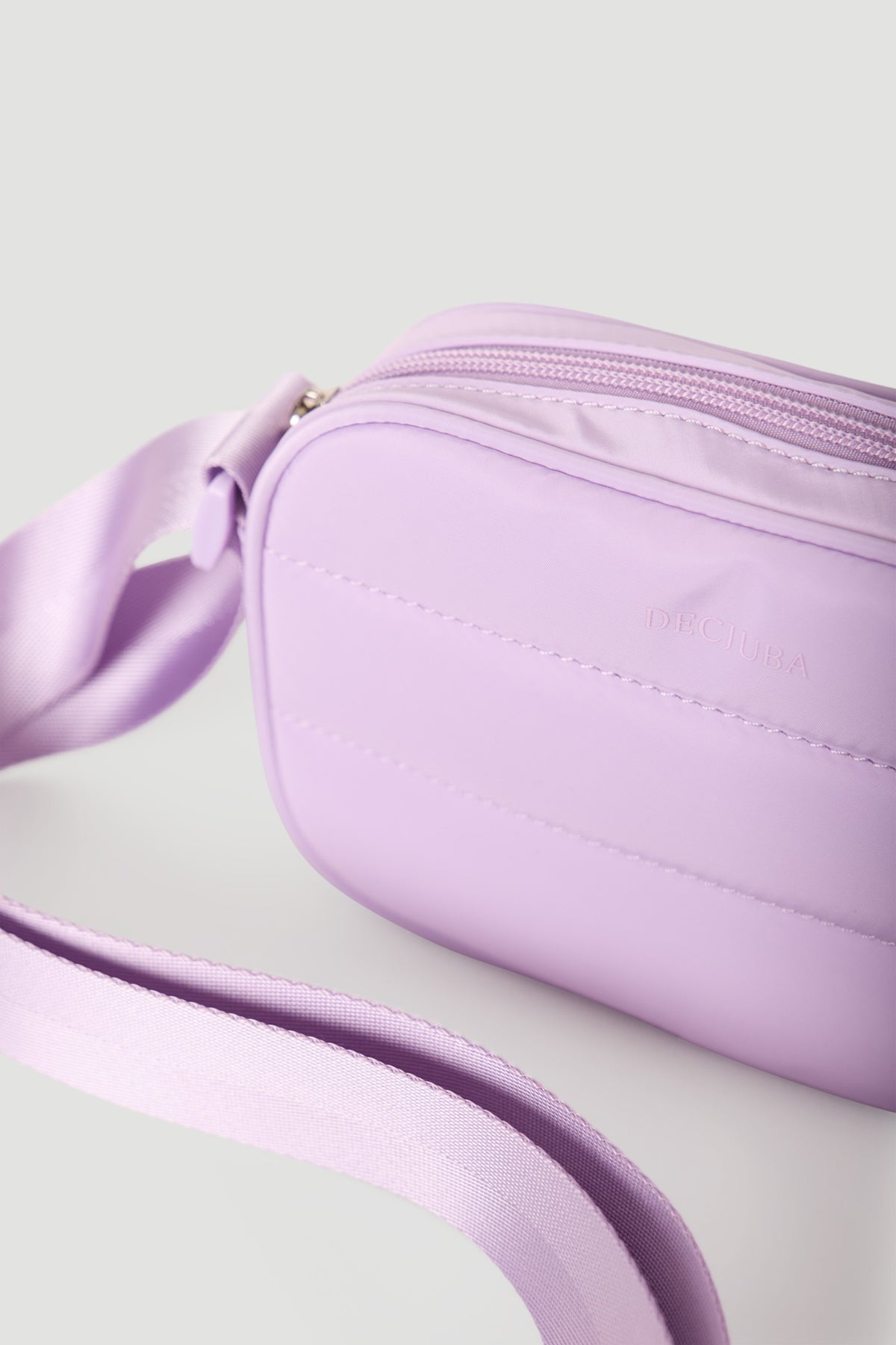 Lilac padded small crossbody bag with adjustable strap and subtle branding detail on front panel.