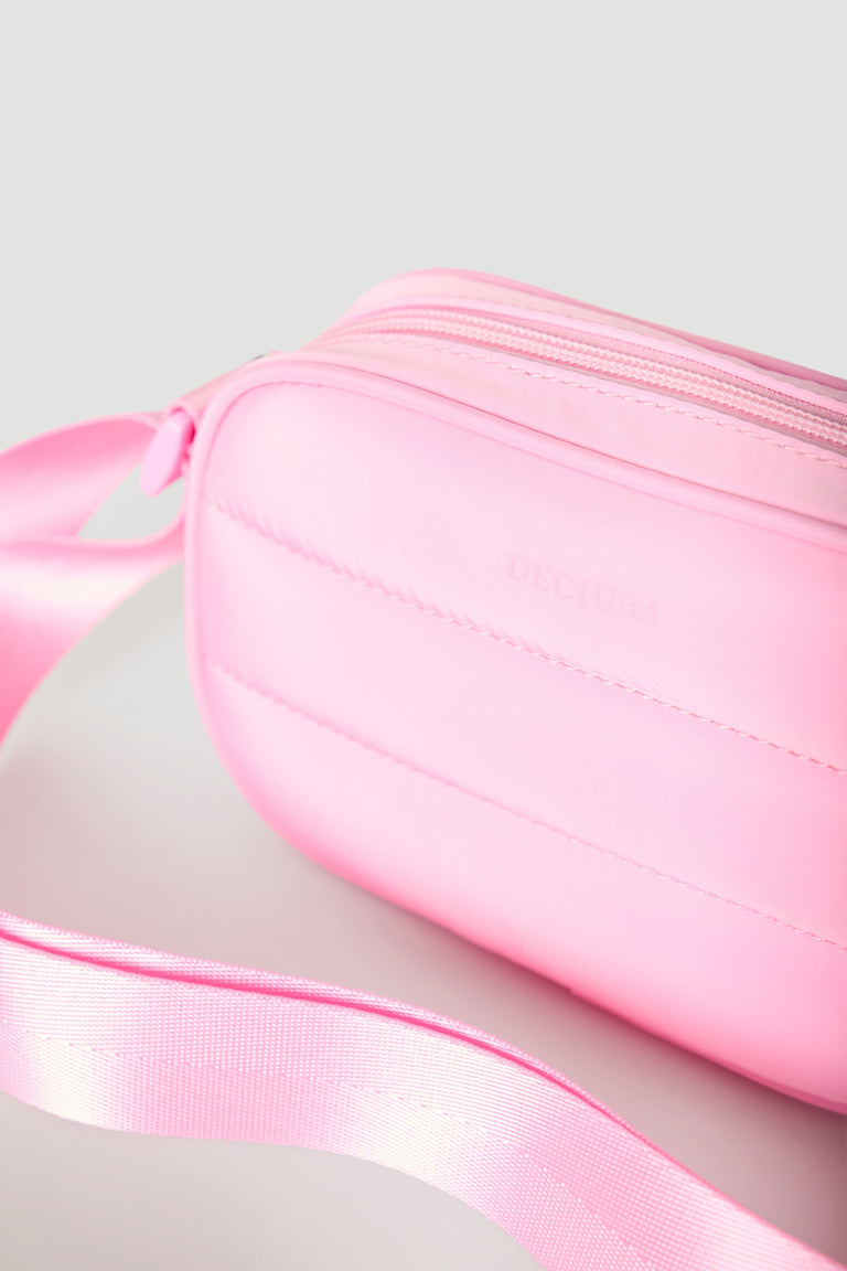 Soft pink padded crossbody bag with a smooth finish and adjustable matching strap for easy wear.