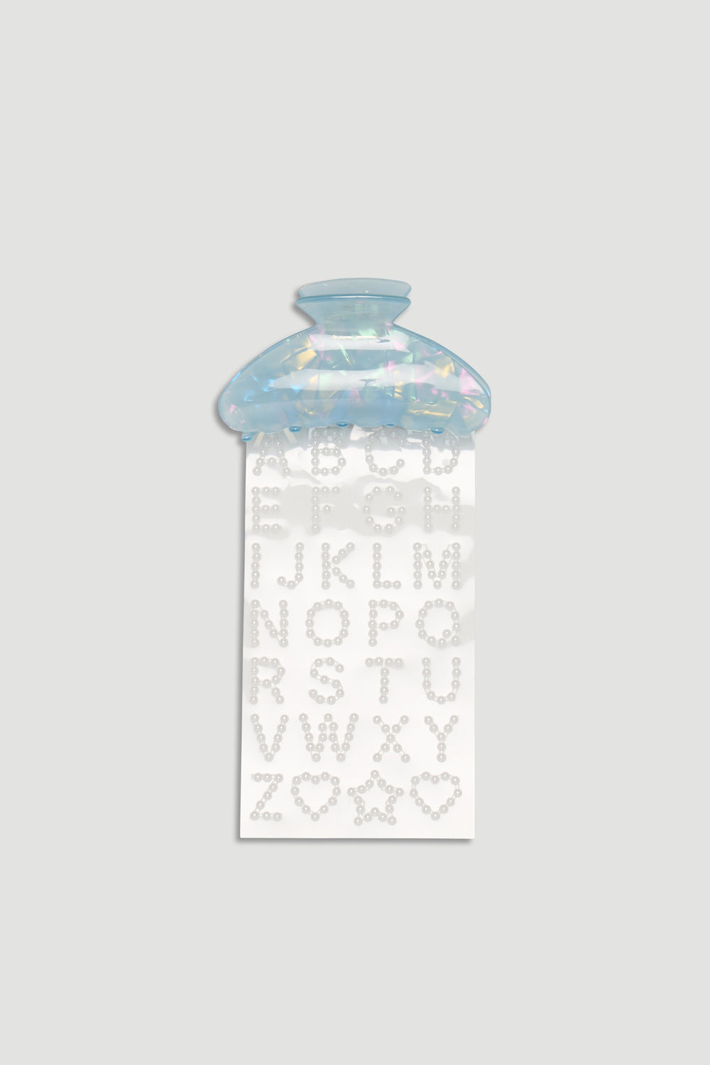 Iridescent blue hair claw clip with a sheet of pearl-like alphabet stickers for creative styling.