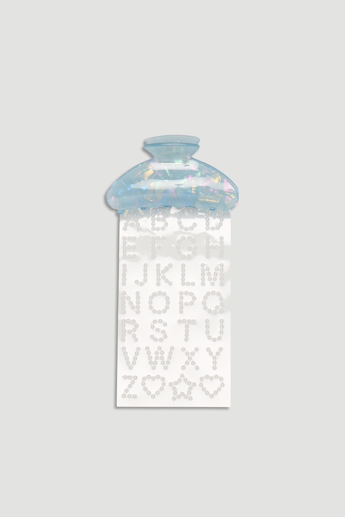 Iridescent blue hair claw clip with a sheet of pearl-like alphabet stickers for creative styling.
