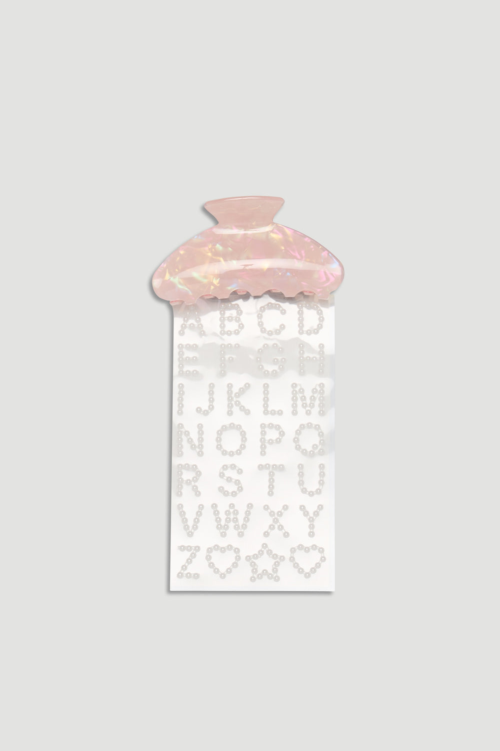 Pink iridescent hair claw clip paired with pearl-studded alphabet and shape stickers for customization.