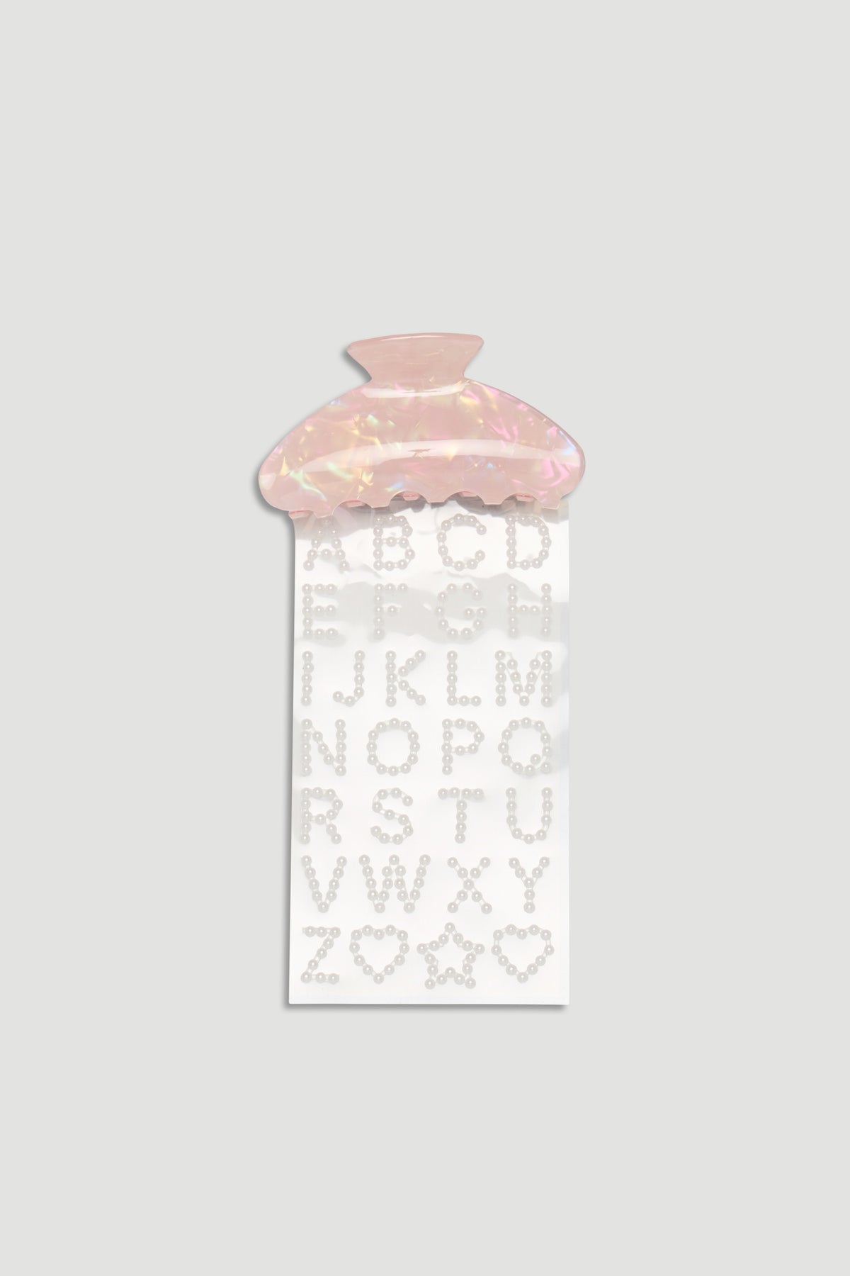 Pink iridescent hair claw clip paired with pearl-studded alphabet and shape stickers for customization.