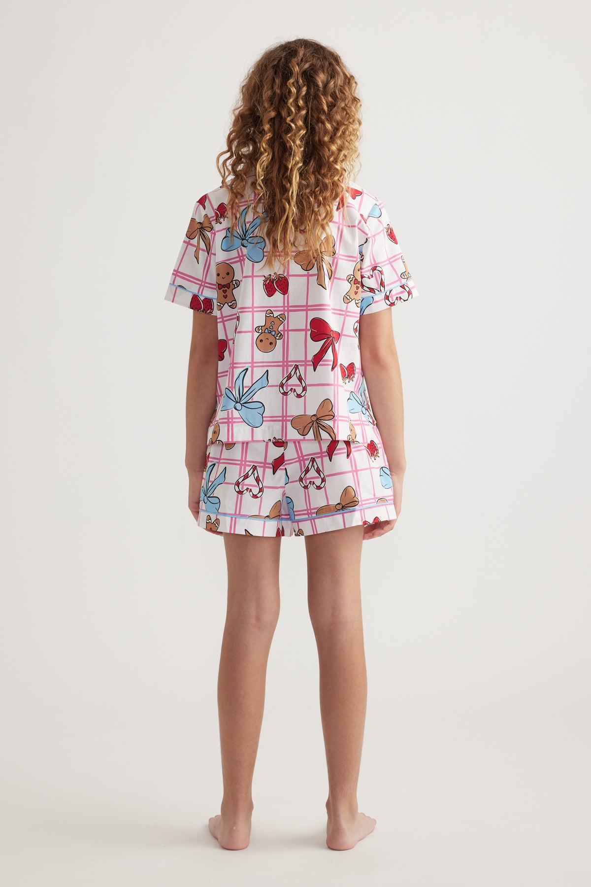 Back view of a girl wearing a pink patterned collared shirt and matching shorts sleep set