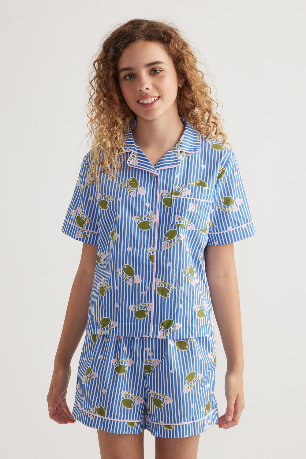 Girl wearing a blue striped collared shirt and matching shorts with a playful fruit print