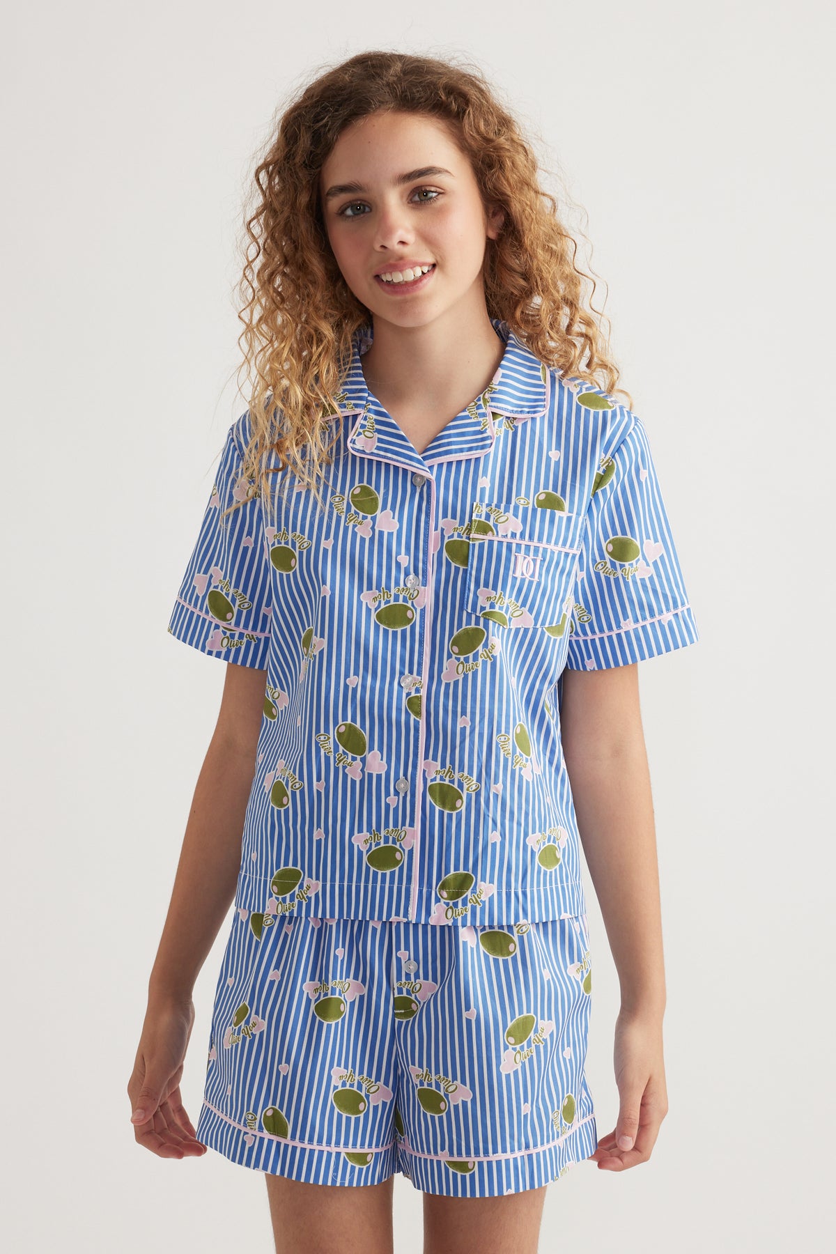 Girl wearing a blue striped collared shirt and matching shorts with a playful fruit print