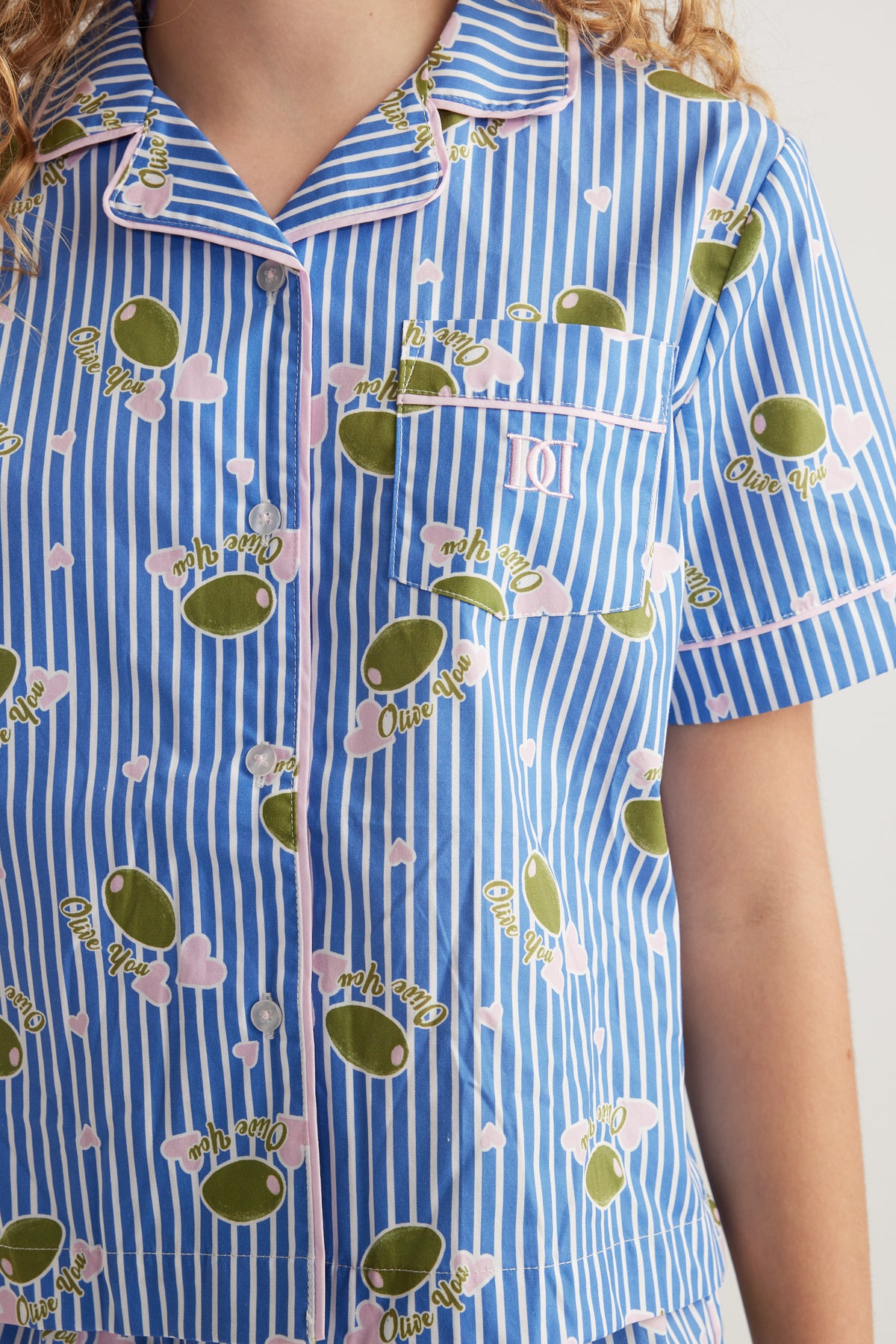 Girl wearing a blue striped short sleeve shirt with fruit print, collar and button front