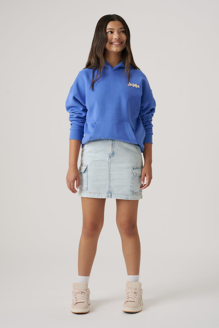 Girl wearing a light wash denim cargo skirt with a blue hoodie and sneakers