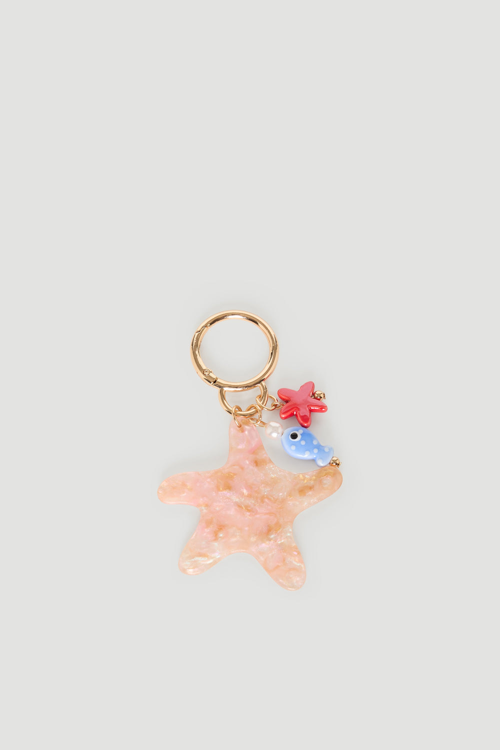 Gold keyring featuring a pink starfish charm with a small blue fish and red coral accents