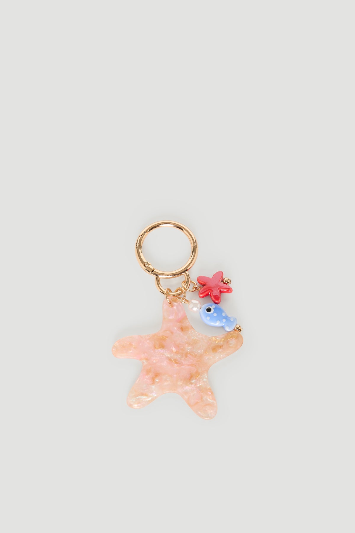 Gold keyring featuring a pink starfish charm with a small blue fish and red coral accents