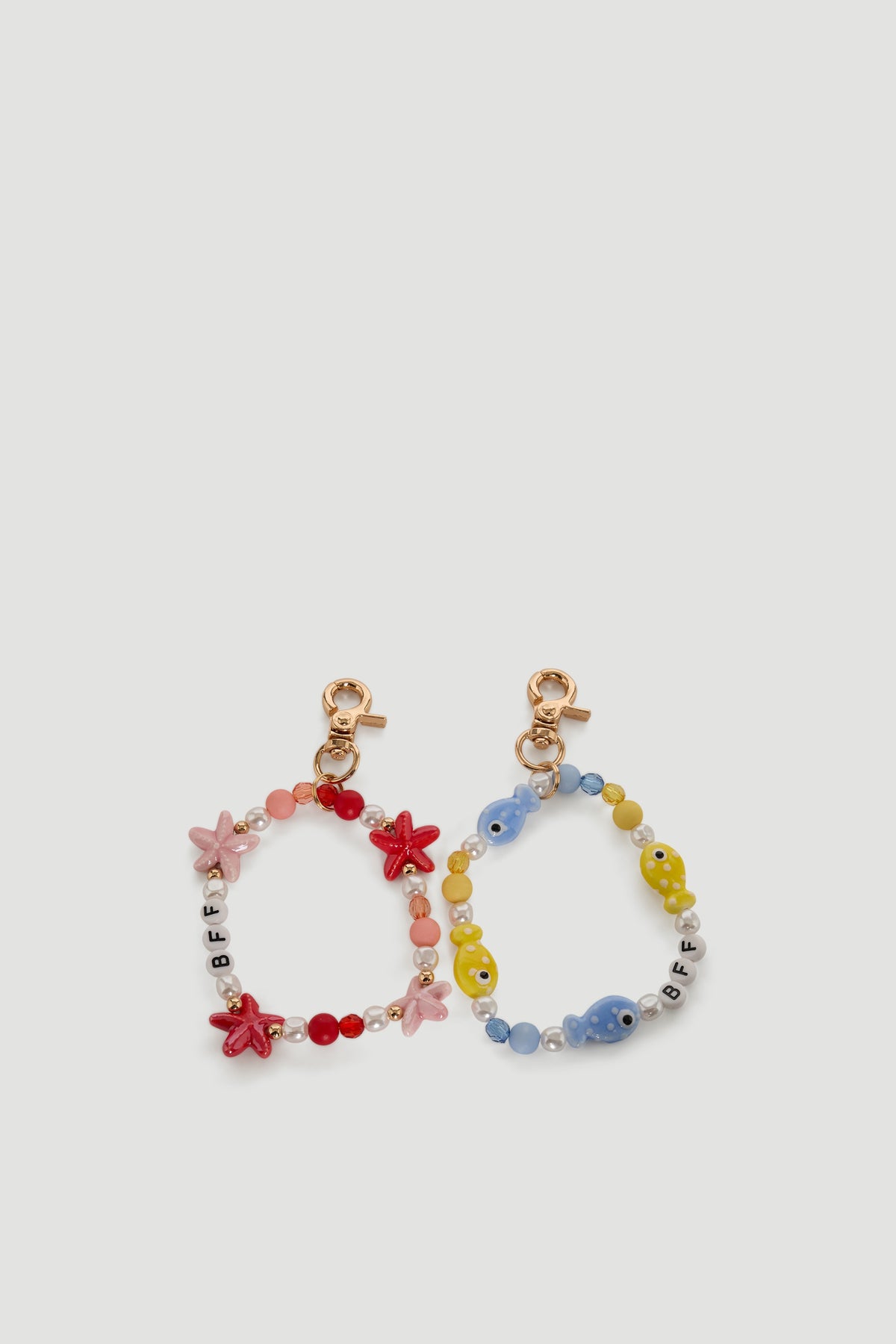 Two colorful beaded bag charms with starfish and fish shapes and gold clip attachments for girls.
