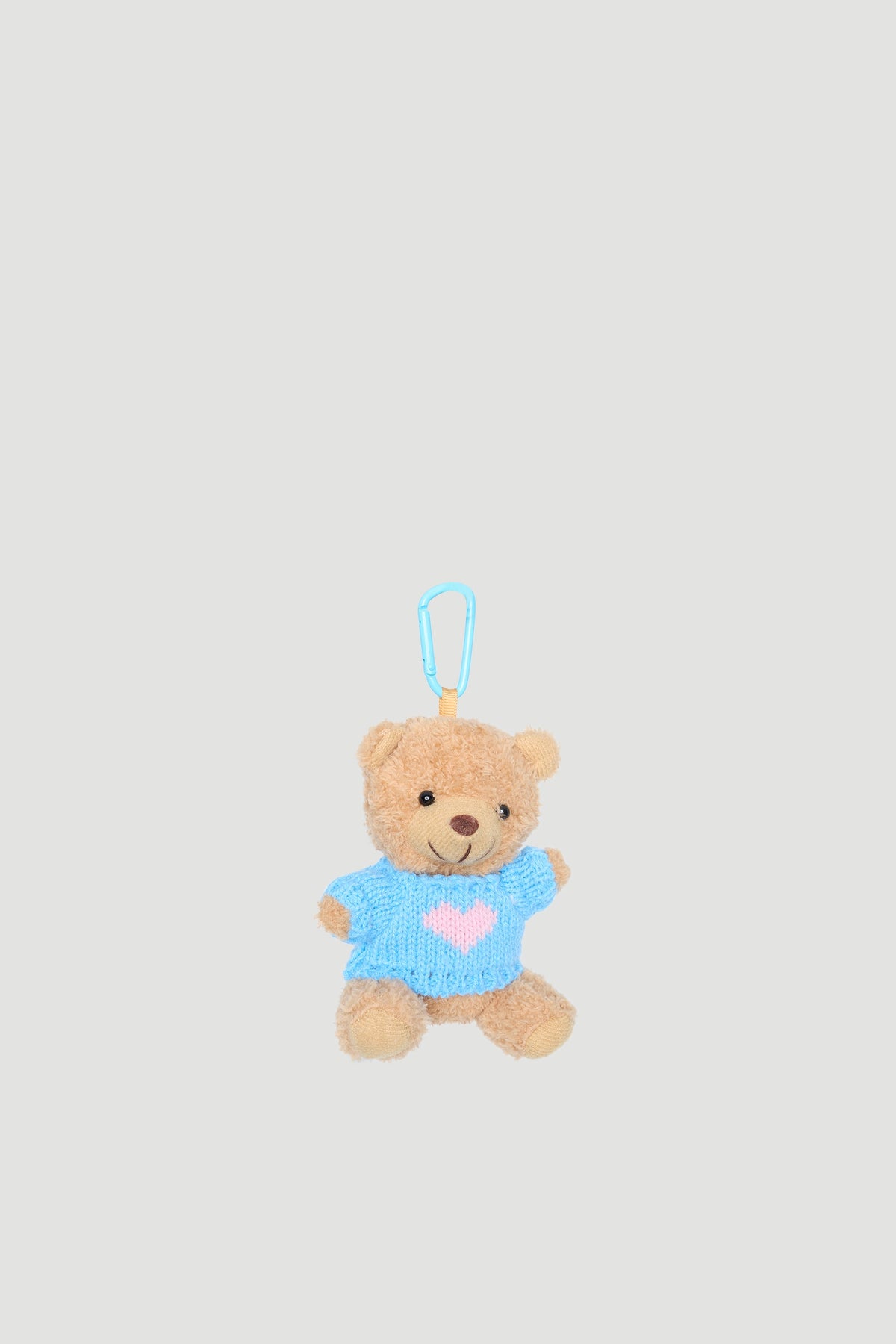 Small plush teddy bear charm wearing a blue sweater with a pink heart and a blue clip attachment