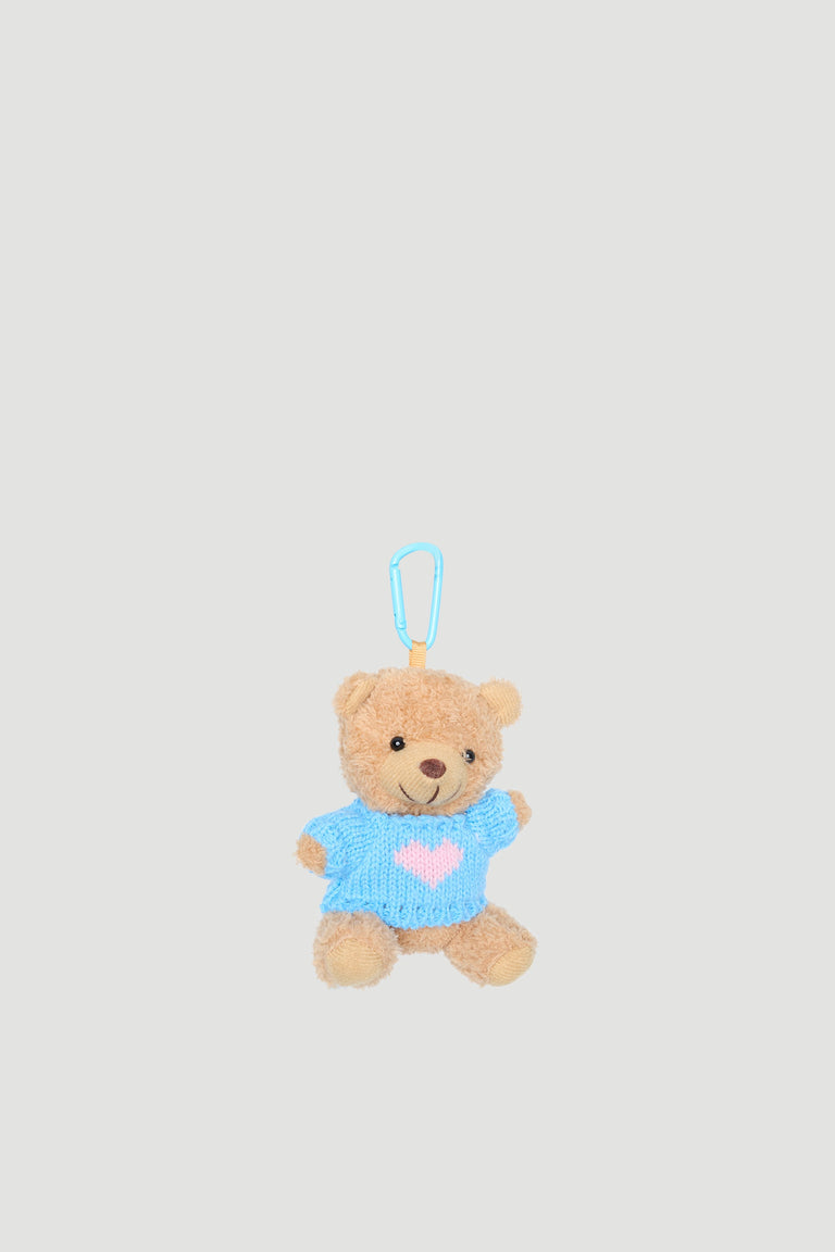 Small plush teddy bear charm wearing a blue sweater with a pink heart and a blue clip attachment