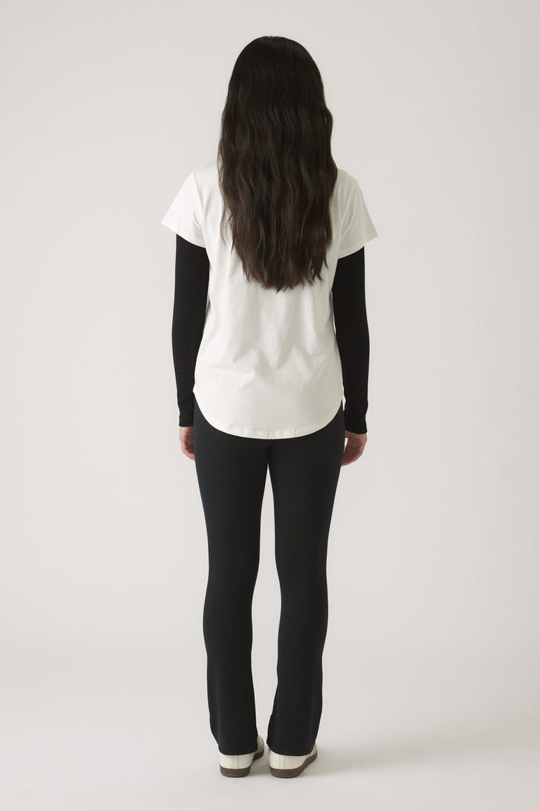 Girl wearing a white short-sleeve tee layered over a black long-sleeve top paired with fitted black pants and white shoes
