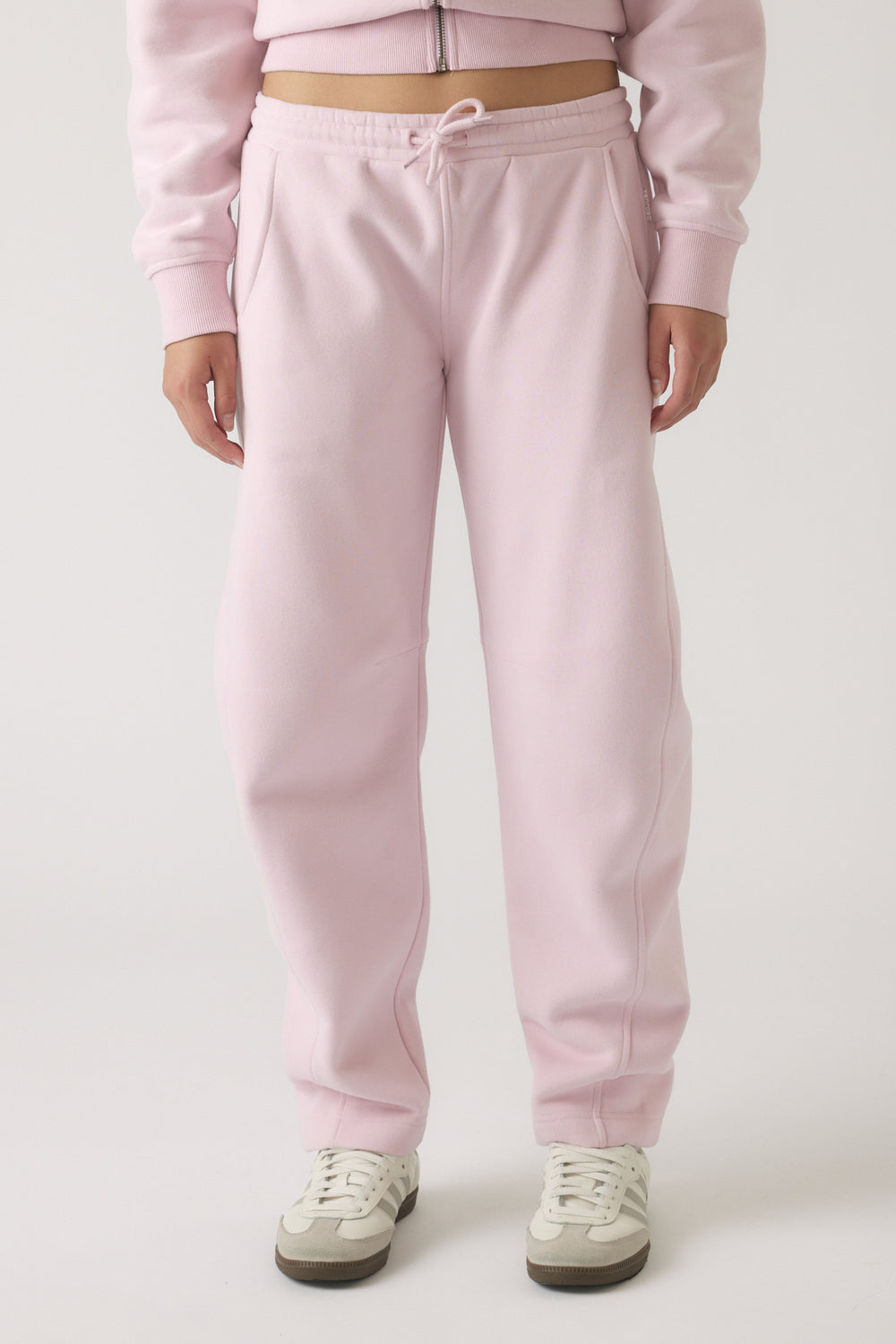 Girls wearing soft mauve barrel leg track pants styled with casual sneakers and a matching zip-up top