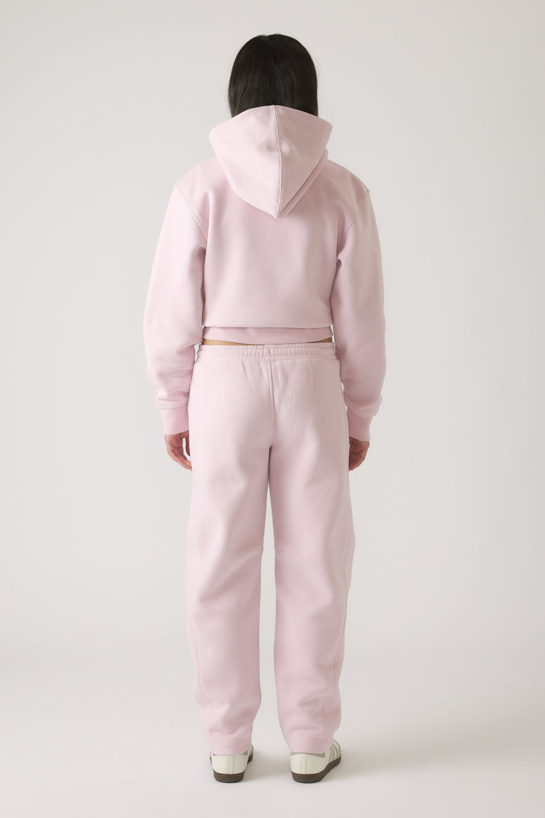 Back view of girl wearing soft mauve barrel leg pants with matching cropped hoodie and casual sneakers.