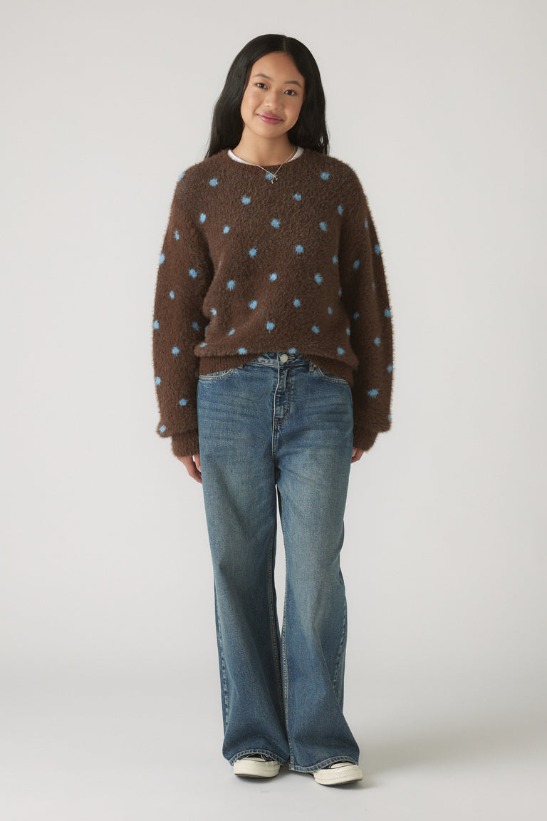 Girl wearing a brown Girls Fluffy Crew Knit Jumper with blue polka dots styled with relaxed blue denim jeans and white sneakers.