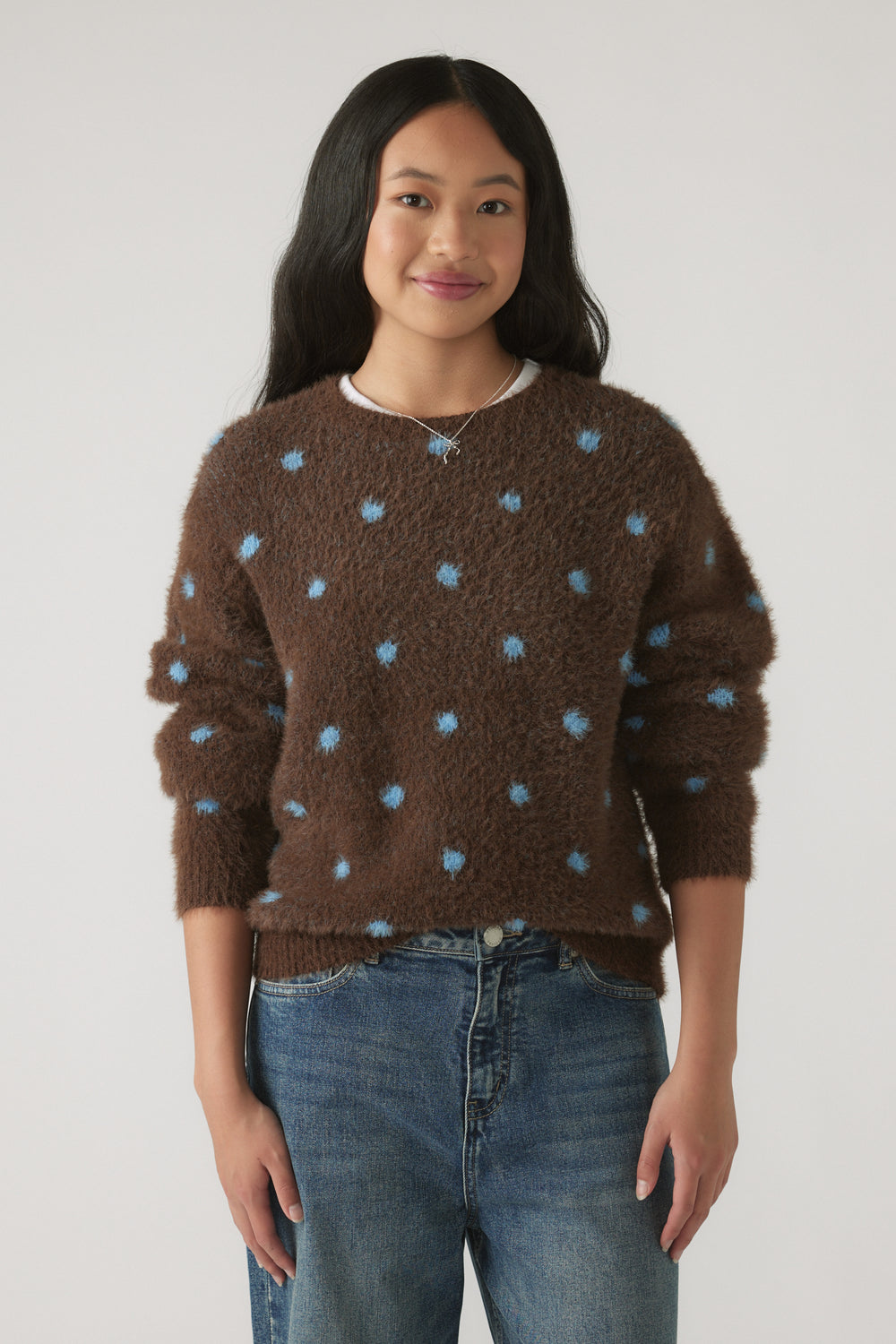 Girl wearing a Girls Fluffy Crew Knit Jumper in brown with soft blue polka dots, styled with casual denim jeans by DECJUBA