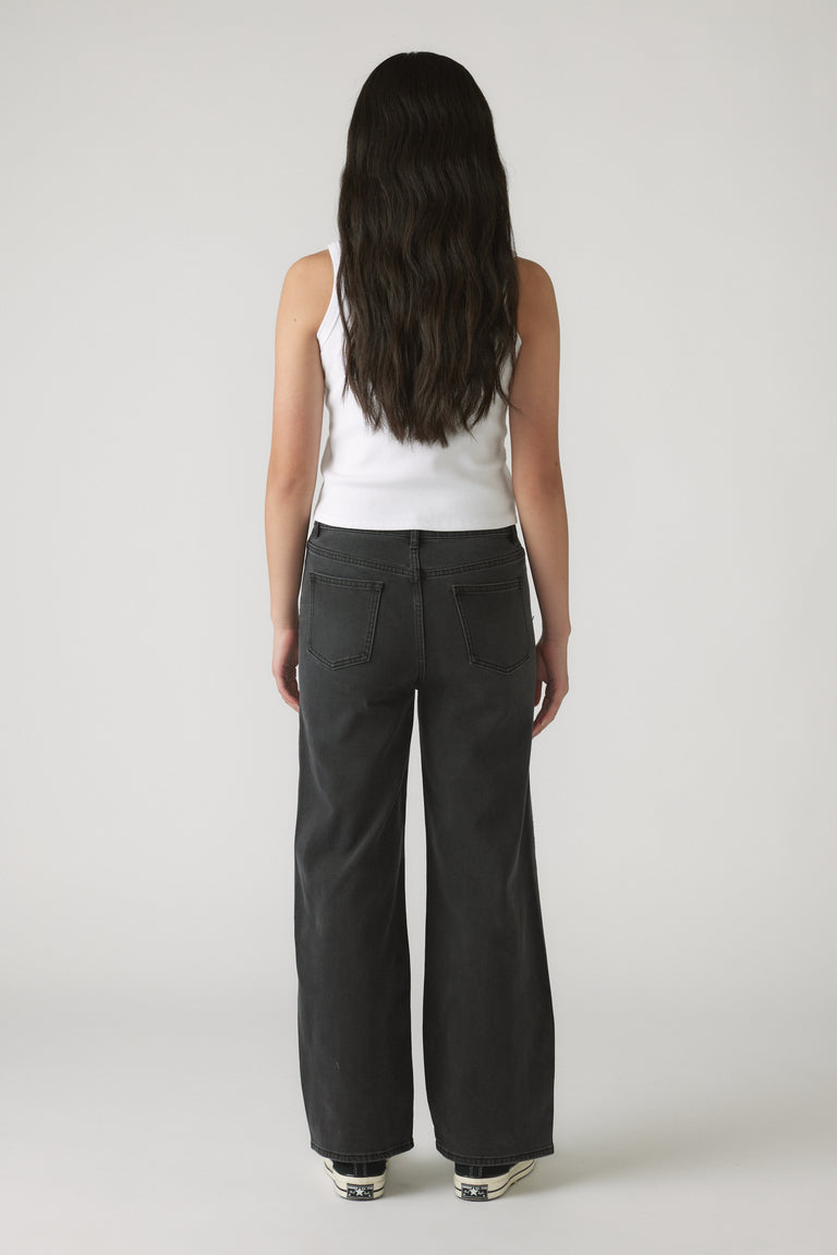 Girl seen from behind wearing black Girls Hailey Extra Long Jean with a relaxed straight-leg fit and casual white tank top