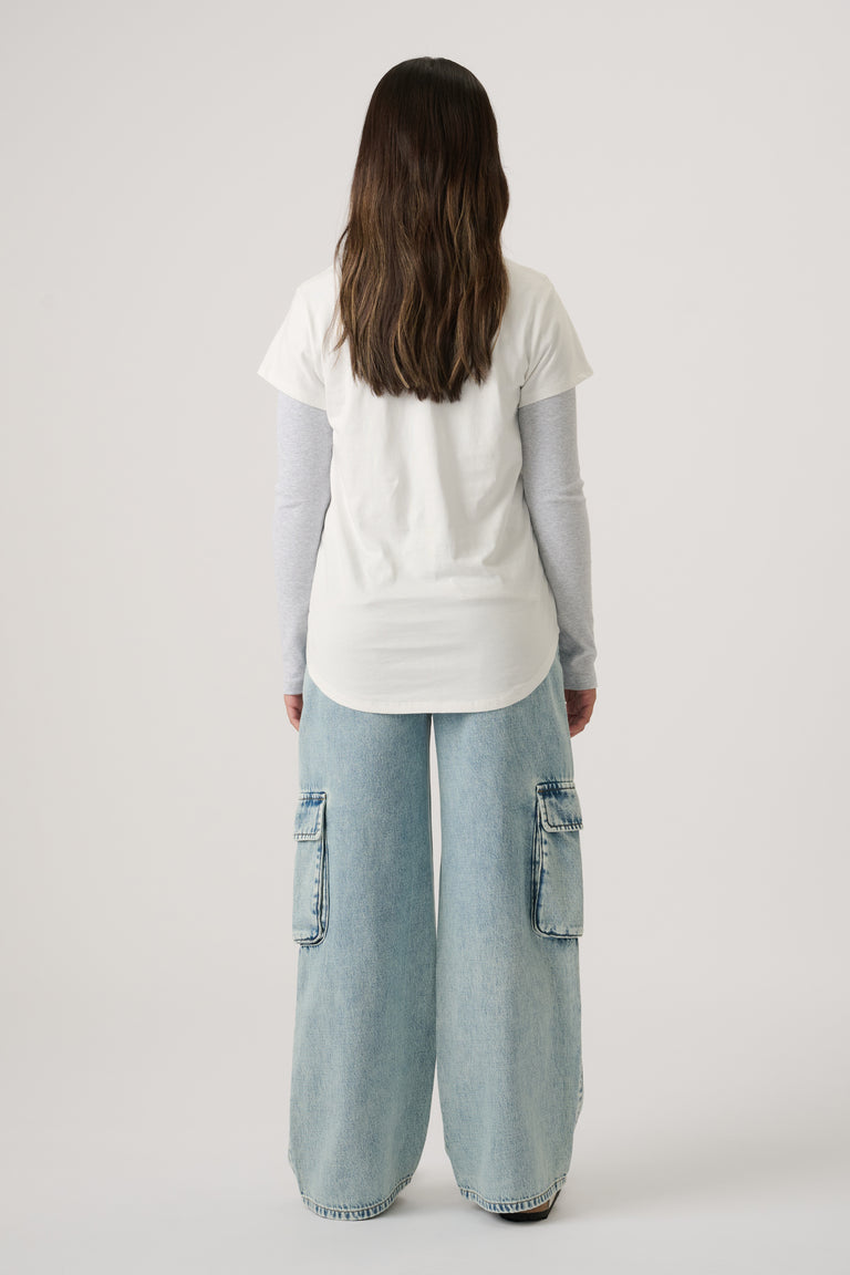 Girl wearing a white tee layered over a long-sleeve top, paired with light wash wide-leg denim cargo jeans.