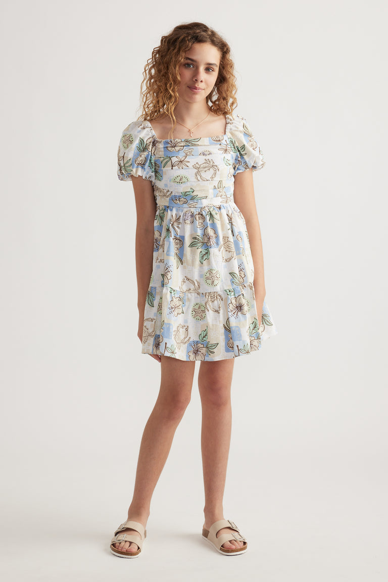 Girl wearing a floral spot print mini dress with puff sleeves, square neckline and tiered skirt