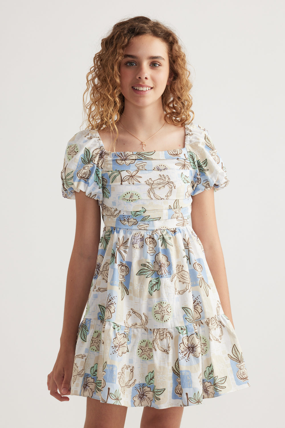 Girl wearing a floral print dress with puff sleeves, square neckline and tiered skirt