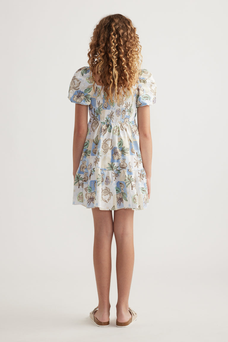 Girl viewed from behind wearing a floral print dress with puff sleeves and a tiered skirt