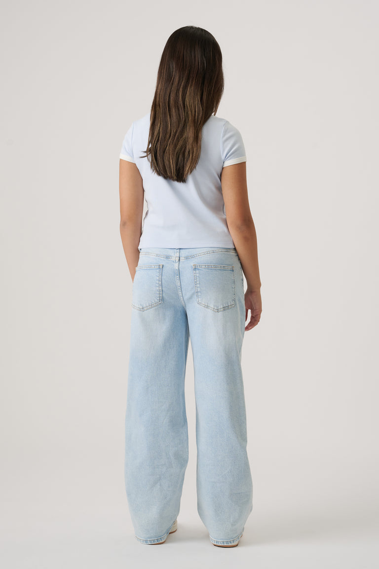 Girl wearing a light blue cropped tee paired with loose, light-wash denim jeans, viewed from the back