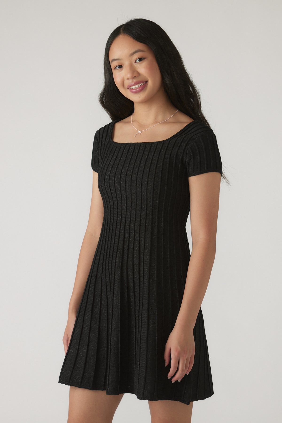 Girl wearing a black ribbed Girls Gemma Knit Dress with short sleeves and a flared skirt silhouette