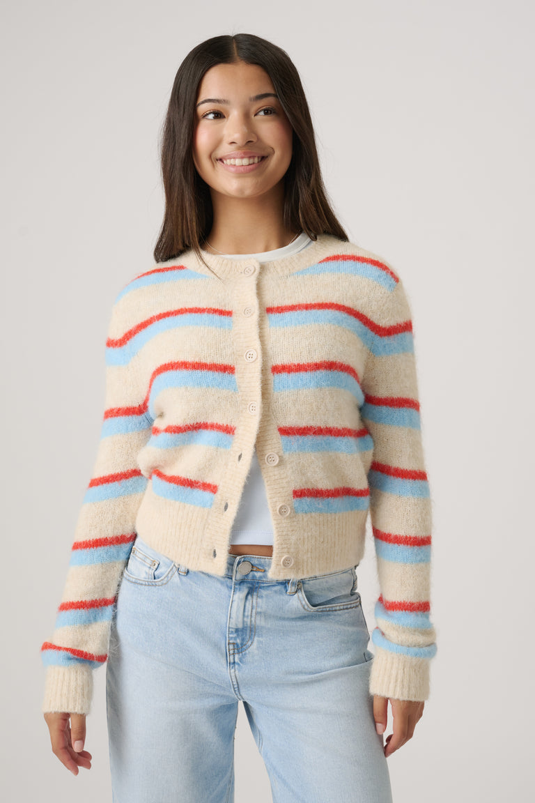 Young woman wearing a cozy cropped cardigan with colorful stripes paired with light wash high-rise jeans, smiling confidently.