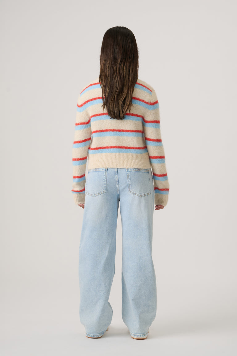 Girl wearing a soft striped cropped sweater paired with light wash wide-leg denim jeans, shown from behind.