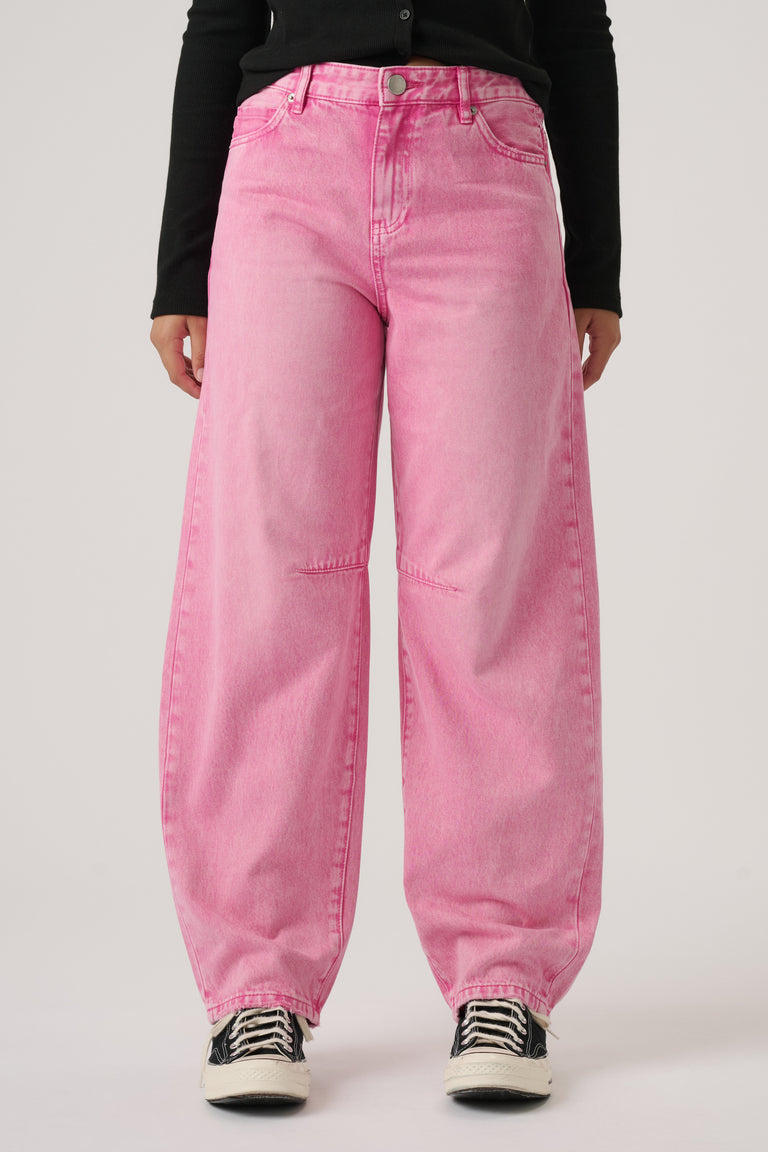 Girl wearing relaxed fit pink denim jeans paired with black long-sleeve top and black and white sneakers