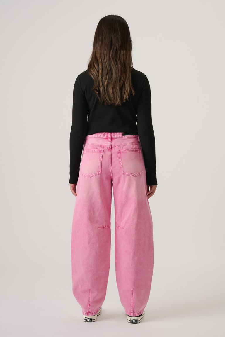 Girl wearing wide-leg pink denim jeans with back pockets and a fitted black long sleeve top