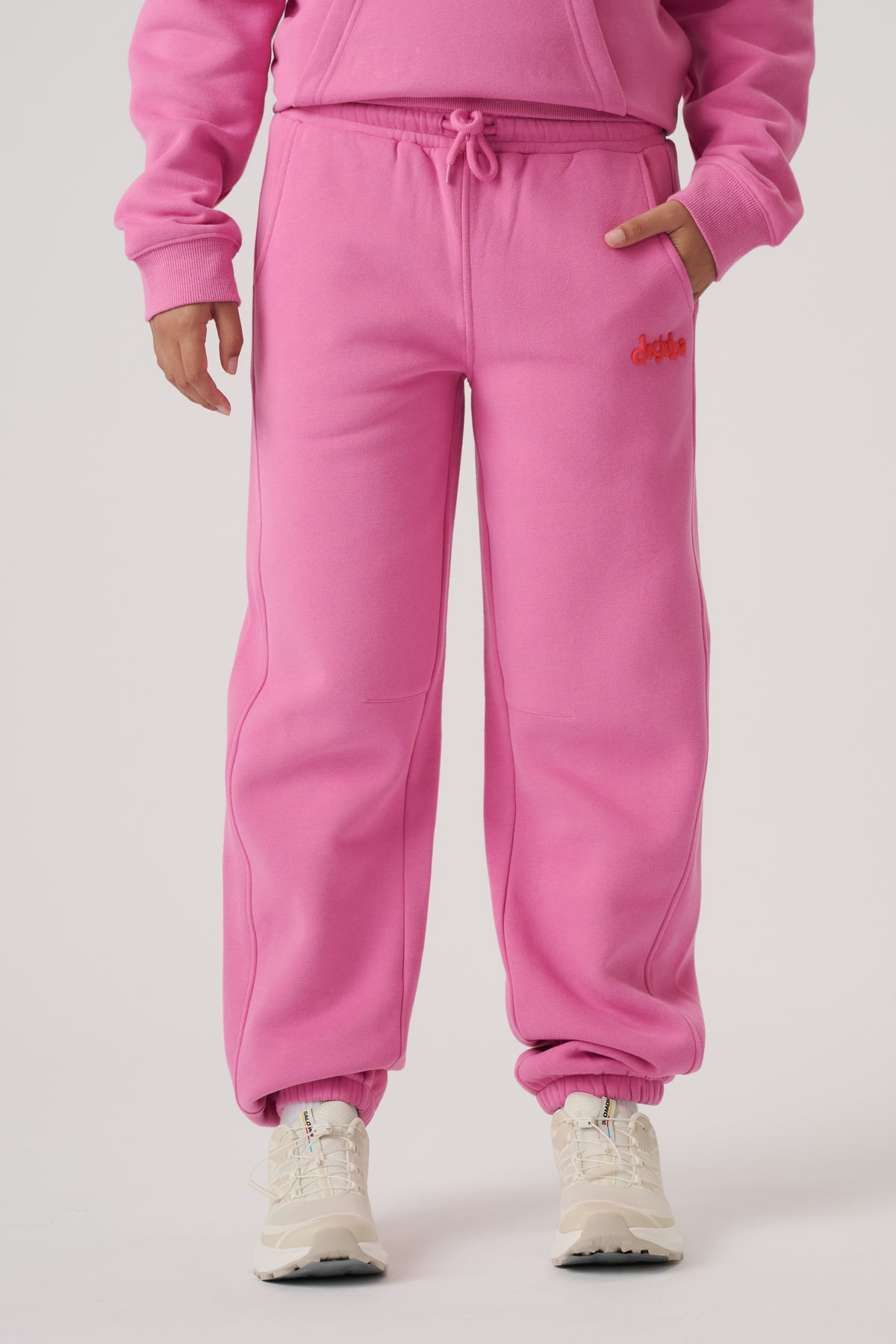Bright pink balloon leg trackpants with elastic cuffs, drawstring waist, side pockets, and sporty embroidered detail.
