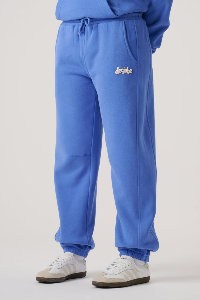 Blue balloon leg trackpants with elastic cuffs, side pockets, and subtle embroidered branding on the hip.