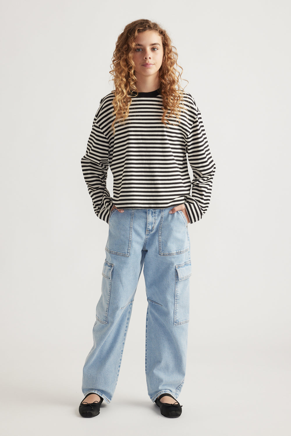 Girl wearing a black and white striped long sleeve tee paired with light wash wide-leg cargo jeans and black flats