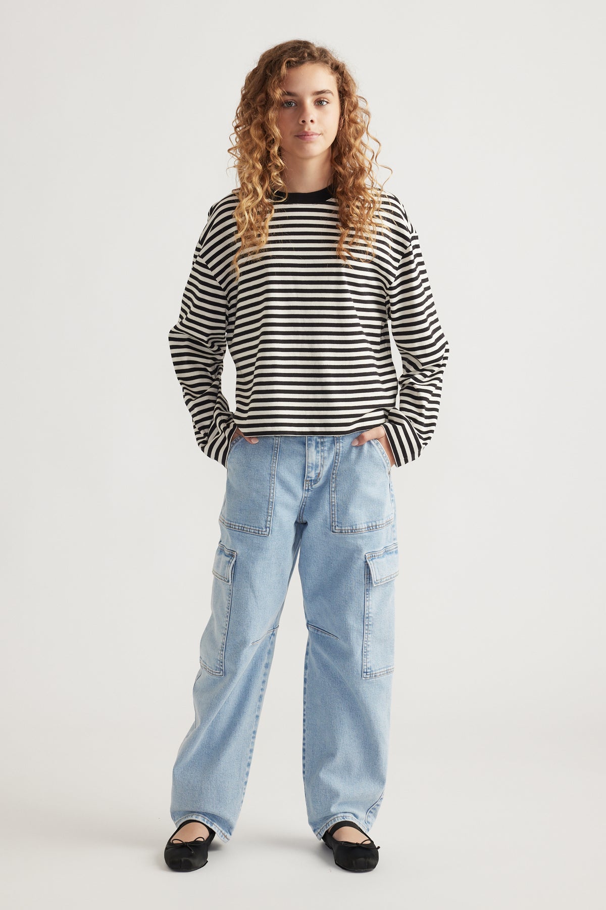 Girl wearing a black and white striped long sleeve tee paired with light wash wide-leg cargo jeans and black flats