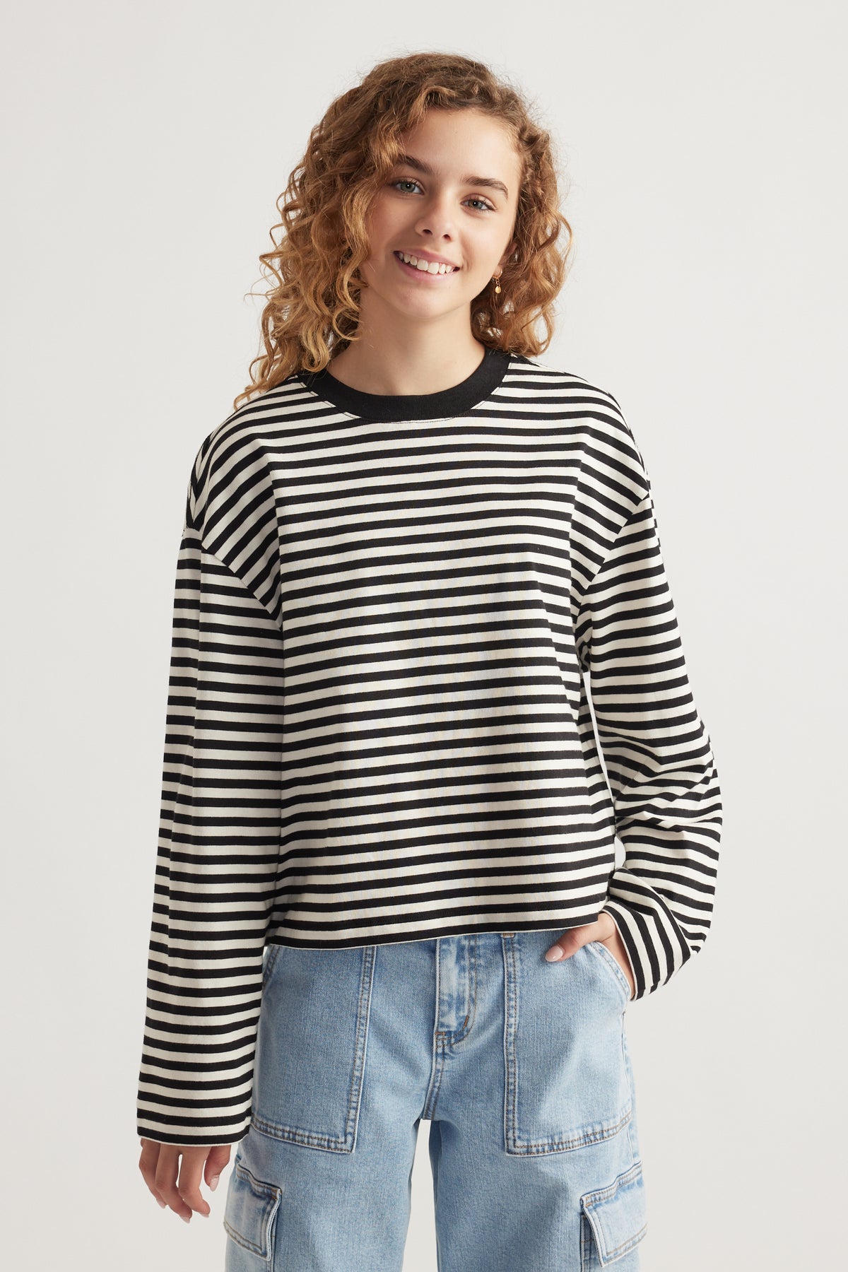 Girl wearing a relaxed fit black and white striped long sleeve tee paired with light blue denim cargo pants