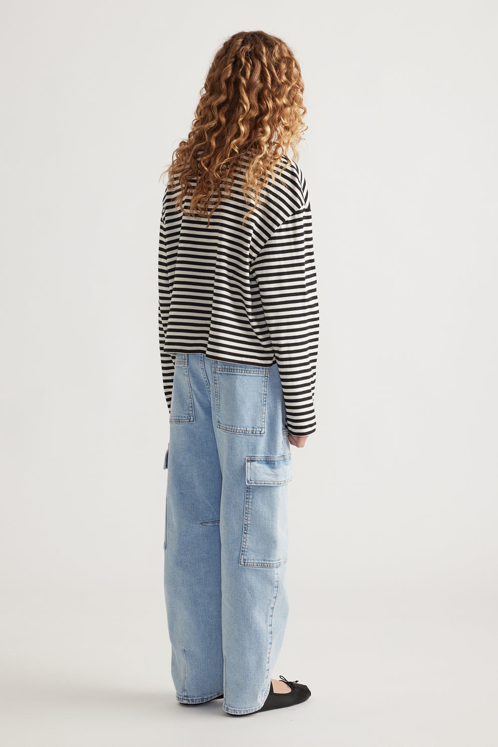 Girl wearing a relaxed fit black and white striped long sleeve tee paired with light blue wide-leg denim pants